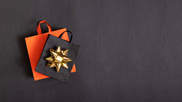 Black friday sale banner with copy space. Red and black paper shopping bags with festive bow on black background.