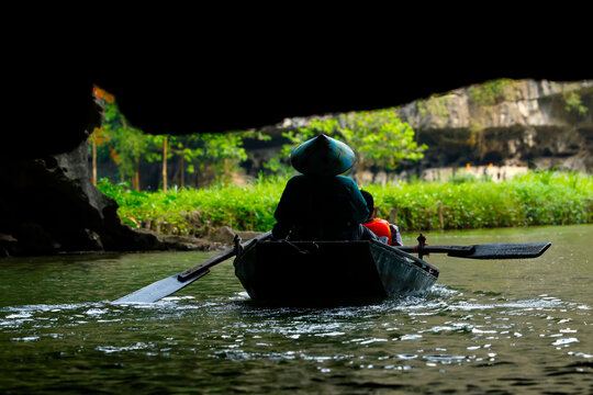 A person is boating on a river, passing through a cave in the Hoa Lu region. Tam Coc, Vietnam.