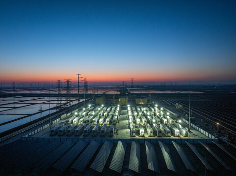 Energy storage station and photovoltaic array under twilight sky with illuminated equipment and coastal wetlands