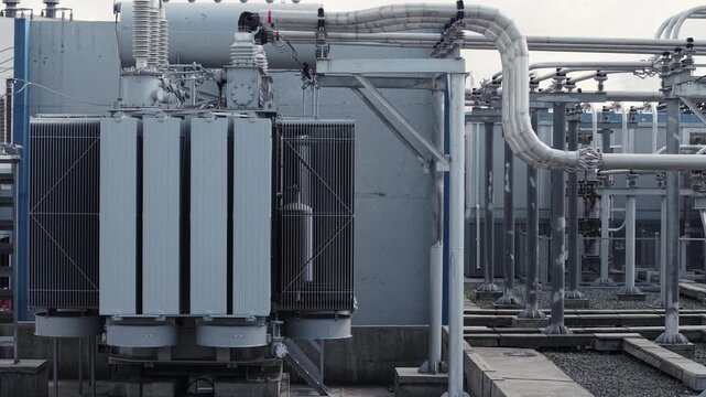 Aerial view large power transformers and connected piping in outdoor electrical substation yard of mining industry.