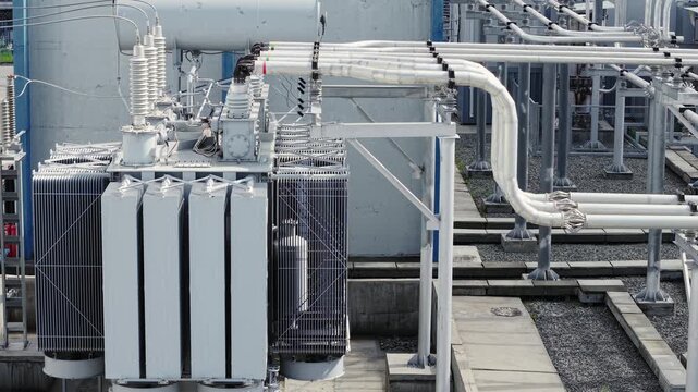 Aerial view of electrical transformers distributing power at outdoor substation rooftop with visible cables and conduits.