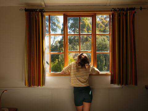 Woman looks out of the window at the forest in Tasmania, Australia 