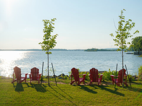 Five iconic Canadian red chairs at the grassy patch near the river 