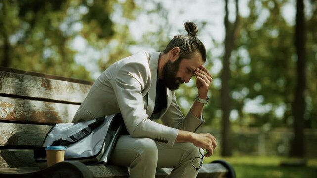 Stressed Businessman Sitting On Wooden Bench In Park. Frustrated Businessman Having Problem Trouble