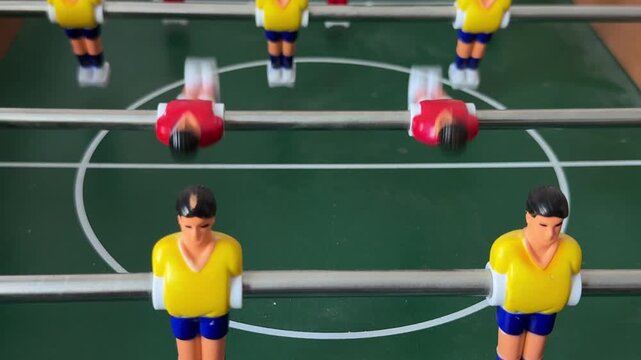 Foosball Table Close-Up with Yellow and Red Players During Match
