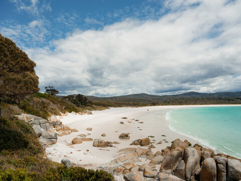 Granite boulders with orange lichen and white sand beach in Tasmania 