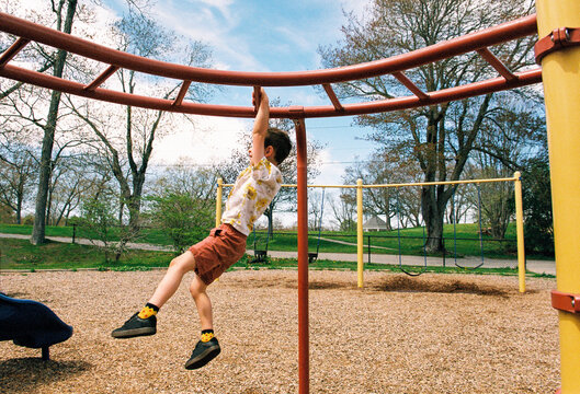 Boy plays on monkey bars at a public playground