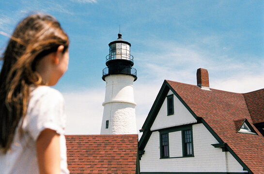 Child on vacation in Maine looks at Portland Head Light lighthouse