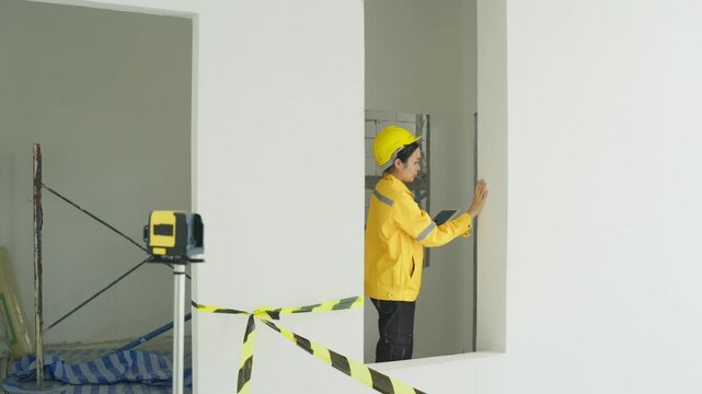 Construction worker yellow safety jacket inspecting interior room renovation, home inspector monitors interior renovation site with caution tape and laser level unfinished room, home inspector yellow
