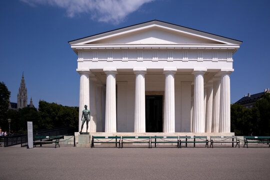 Facciata del Tempio di Teseo in stile neoclassico nel parco Volksgarten a Vienna incorniciata da cespugli di rose fiorite in una giornata di sole estiva, Austria.