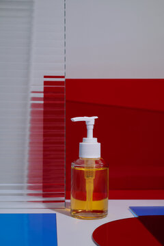 Clear liquid in a pump bottle with red and white abstract background