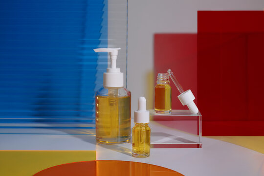 Cosmetic serum bottles with droppers and pump dispenser on glass