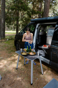 Woman in sportswear setting up a picnic table outside a van