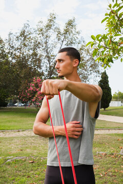 Man Exercises With Resistance Bands in a Park