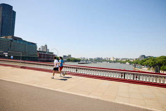 Friends run across the bridge spanning the Thames river