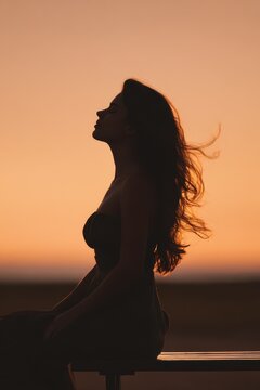 Calm moment: profile silhouette of a woman resting on a bench at sunset