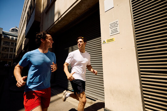 Active Men Run Together on a Sunny Street