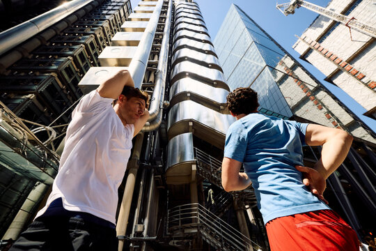 Active men warm up themselves in front of tall buildings