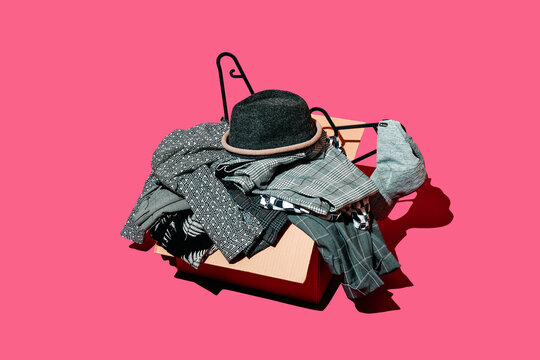 a box of black, white and gray clothes sits on a hot pink backdrop