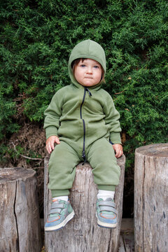 Child Sitting on Wooden Stump Wearing Green Hoodie