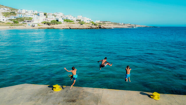 Kids jumping into clear turquoise sea at kythira