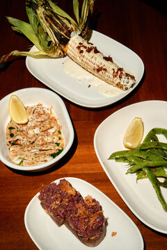Grilled Corn and Gourmet Small Plates Served on Wooden Table