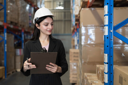 Female warehouse worker checking incoming items on shelf pallet at storage warehouse