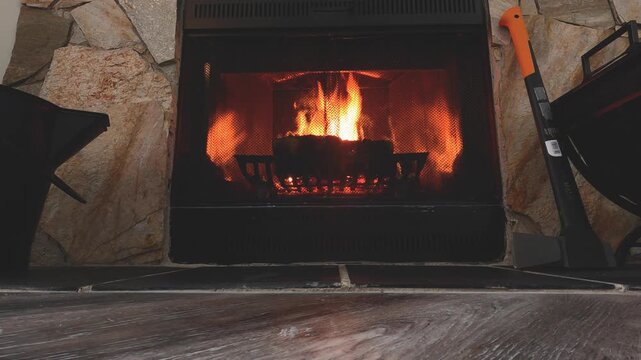 Warm Cozy Fireplace with Burning Firewood and Glowing Flames in Rustic Stone Hearth During Winter. Perfect for winter, home comfort, holiday, Christmas, and cozy living room background videos