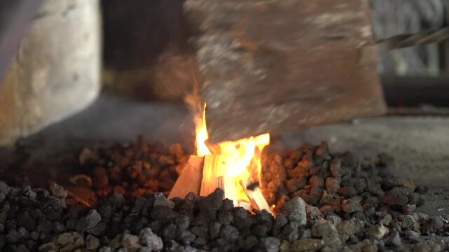 A Captivating Display of Fire's Dance: Flames Flicker and Glow Amidst Charcoal as Wood Splits and Sparks Fly in a Rustic Setting
