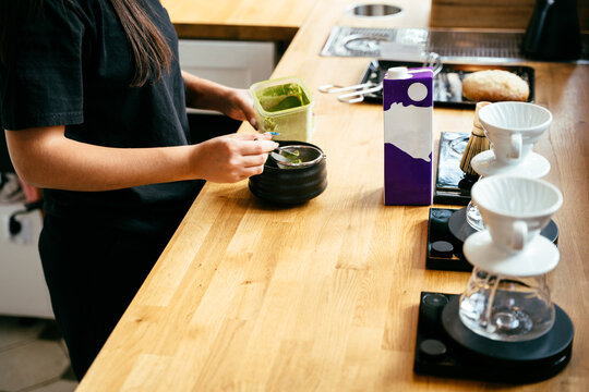 Focused barista preparing matcha drink with traditional tools at specialty coffee shop