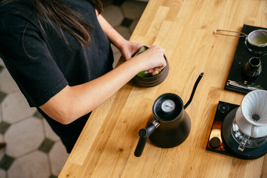Skilled barista whisking green matcha tea with traditional bamboo whisk at specialty cafe