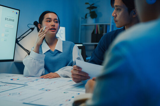 Asia businesspeople presentation sales meeting plan statistics brainstorm and work with paperwork around table in office conference room at night. Business finance partner strategy investment success.