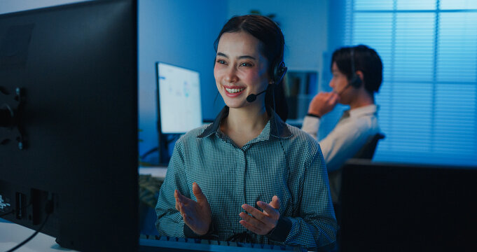 Gen z Asia young call center team or customer support service executive use computer and microphone headset work technical e commerce support in late night office. Telemarketing or sales job concept.