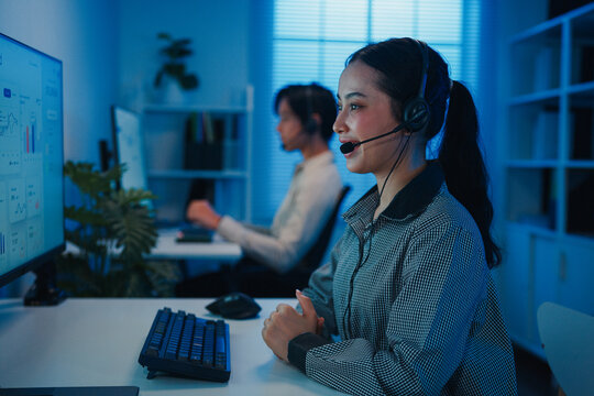 Gen z Asia young call center team or customer support service executive use computer and microphone headset work technical e commerce support in late night office. Telemarketing or sales job concept.