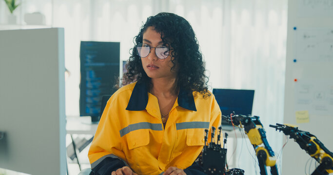 Young Black female engineer coding AI robot arm in modern laboratory. Robotics, artificial intelligence, technology, stem, future, innovation, diversity, automation, machine learning concept.