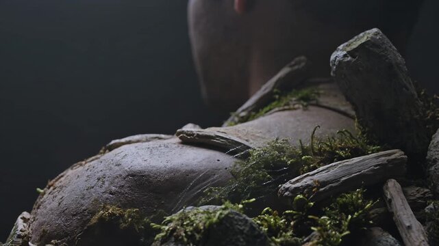 Close-up low angle of a nature-covered forest guardian sparkling with dust in a dark mysterious setting.