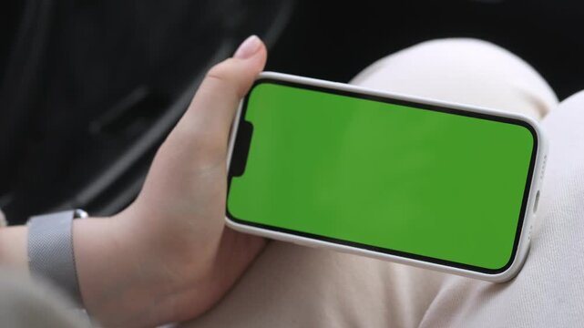 Person holds phone with green screen. Finger taps screen twice. Focus on device and hands. Ideal for app ads or digital content. Casual, neutral emotion. Suitable for UI, tech, or mobile marketing