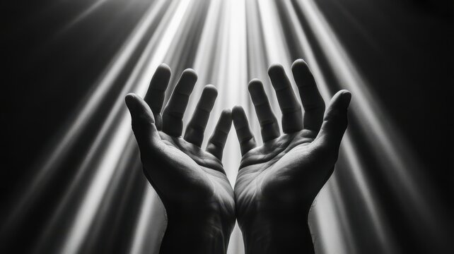 Hands reaching up in dramatic light rays, black and white