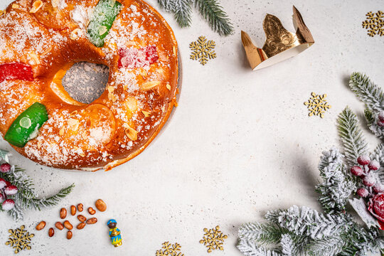 Roscon de reyes with cream and christmas ornaments on a white background, top view. Roscon is a traditional Spanish Christmas pastry cake with decoration. Kings day concept spanish three kings cake.