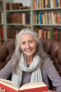 Smiling older woman reading in a leather armchair in a home library for wellness banner and peaceful lifestyle background design