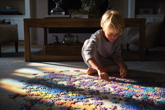 A child puts together a puzzle on the living room floor