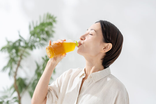 ペットボトルのお茶を飲む女性
