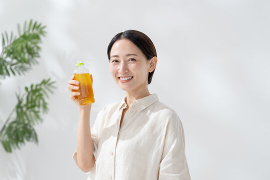 ペットボトルのお茶を飲む女性