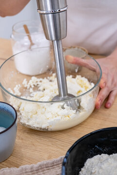 Home cooking. Blender tool. Female chef hand preparing soft cottage cheese meal in glass bowl on table. Immersion culinary appliance work.