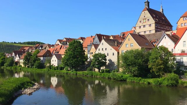 Idyllic village of Besigheim, Germany. Riverside view with reflections old town hall and vineyards in the background. Panning motion.