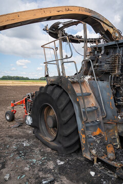 Ausgebrannter Feldh&auml;cksler mit zerst&ouml;rtem Cab, plattem Reifen und Aufstiegstreppe in Detailansicht.