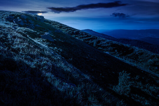 mountain landscape in summer at night. mysterious outdoor scenery of carpathian mountains. full moon over grassy slopes with rocks. fantasy image for ukraine travel background