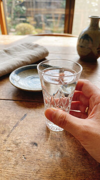 Hand holding crystal sake glass filled with premium Japanese rice wine. Modern presentation of Nihonshu for World Sake Day toasts, hospitality and celebrations