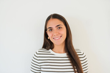 Obraz premium Smiling young woman wearing a striped sweater poses for a natural headshot against a clean white background, conveying warmth, confidence and approachability in a simple lifestyle portrait.