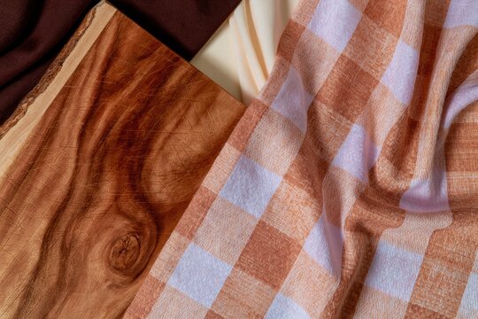 Rustic wooden cutting board with visible grain and scratches on a checkered cloth flat lay for kitchen food preparation and branding mockup